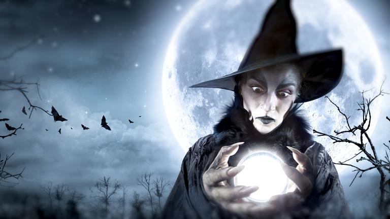 Eine Hexe hält eine Glaskugel in den Händen, im Hintergrund der Vollmond, Fledermäuse.