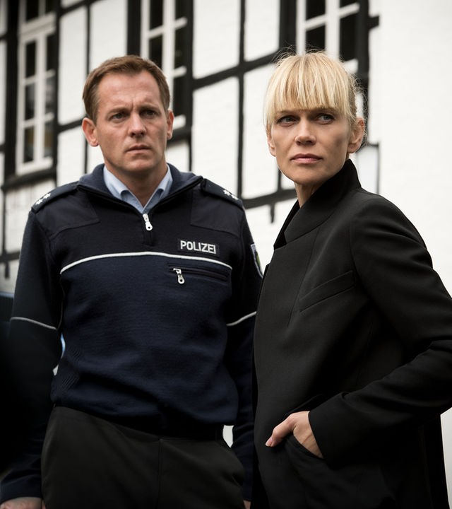 „Helen Dorn – Nach dem Sturm“: Tom Petersen (Johannnes Zirner) und Helen Dorn (Anna Loos) stehen nebeneinander im Freien vor einem weißen Haus.