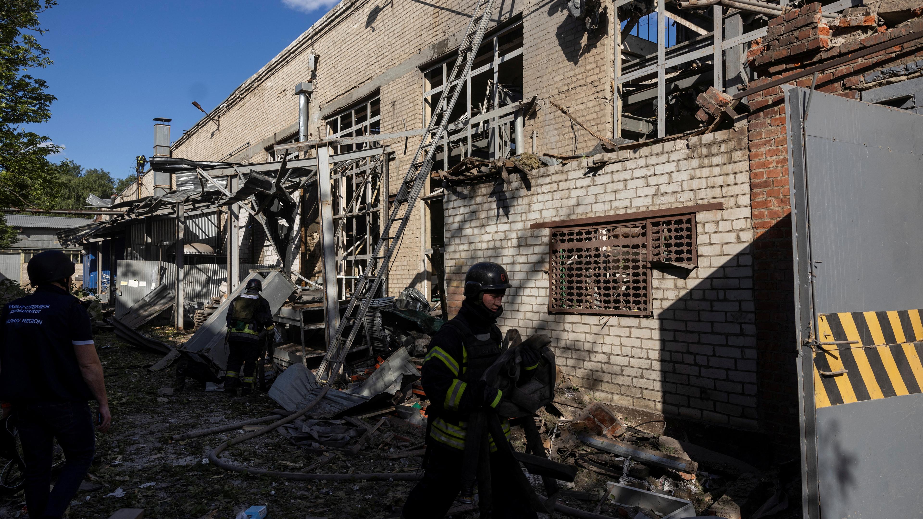 Feuerwehrleute und ein Staatsanwalt für Kriegsverbrechen arbeiten am Standort einer landwirtschaftlichen Gerätefabrik, die während des russischen Angriffs auf die Ukraine am 27. Mai 2024 in Charkiw, Ukraine, von einem russischen Luftangriff getroffen wurde. 