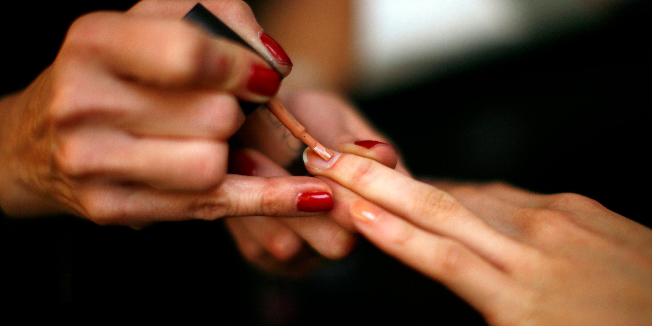 Eine Frau lackiert ihre Fingernägel mit rotem Nagellack
