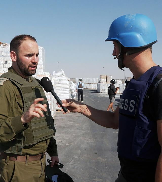 Ein Pressevertreter spricht mit einem Mann in olivgrüner Kleidung 