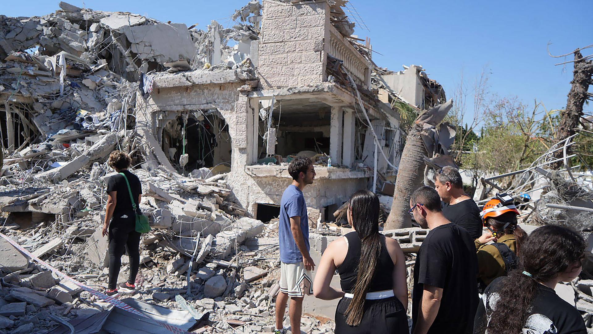 Menschen gehen am 14.06025 durch die Trümmer eines zerstörten Gebäudes in Rischon LeZion (Israel)