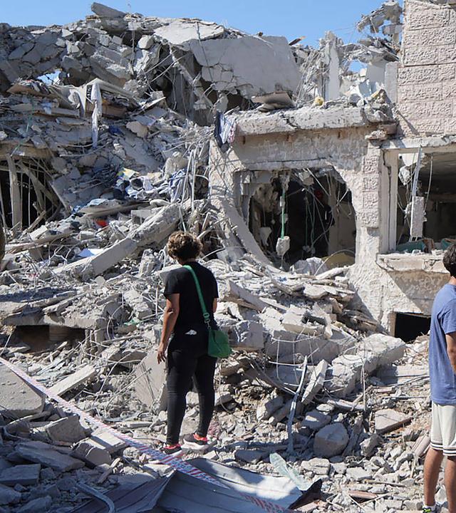 Menschen gehen am 14.06025 durch die Trümmer eines zerstörten Gebäudes in Rischon LeZion (Israel)