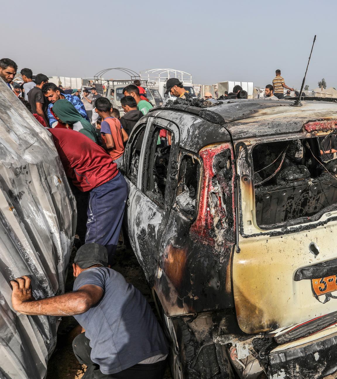 Palästinensische Gebiete, Rafah: Palästinenser inspizieren ein ausgebranntes Auto nach einem israelischen Luftangriff auf ein Flüchtlingslager.