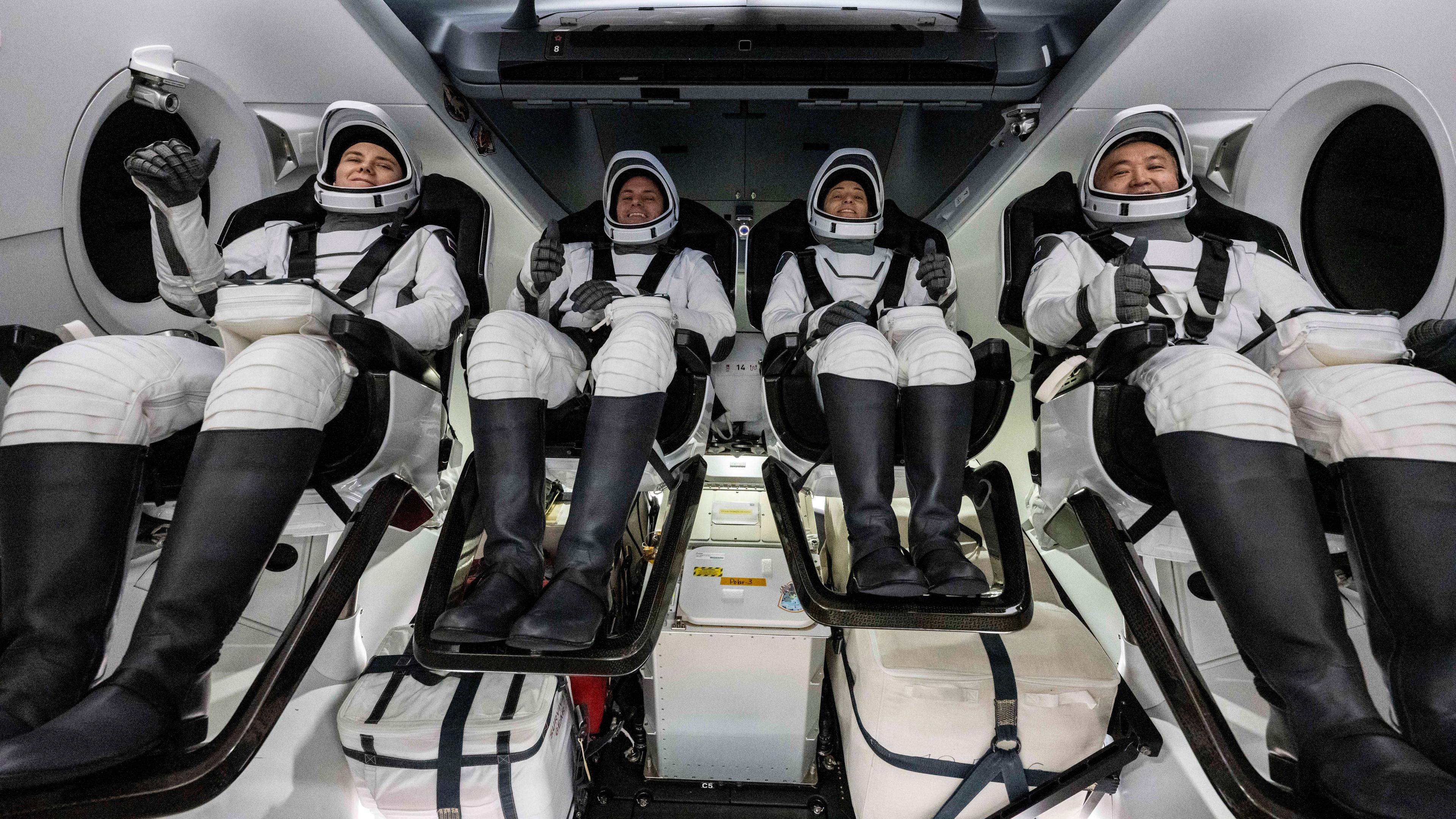 Vier Astronauten und Astonautinnen sitzen in einer SpaceX-Kapsel kurz nach ihrer Landung zurück auf der Erde.