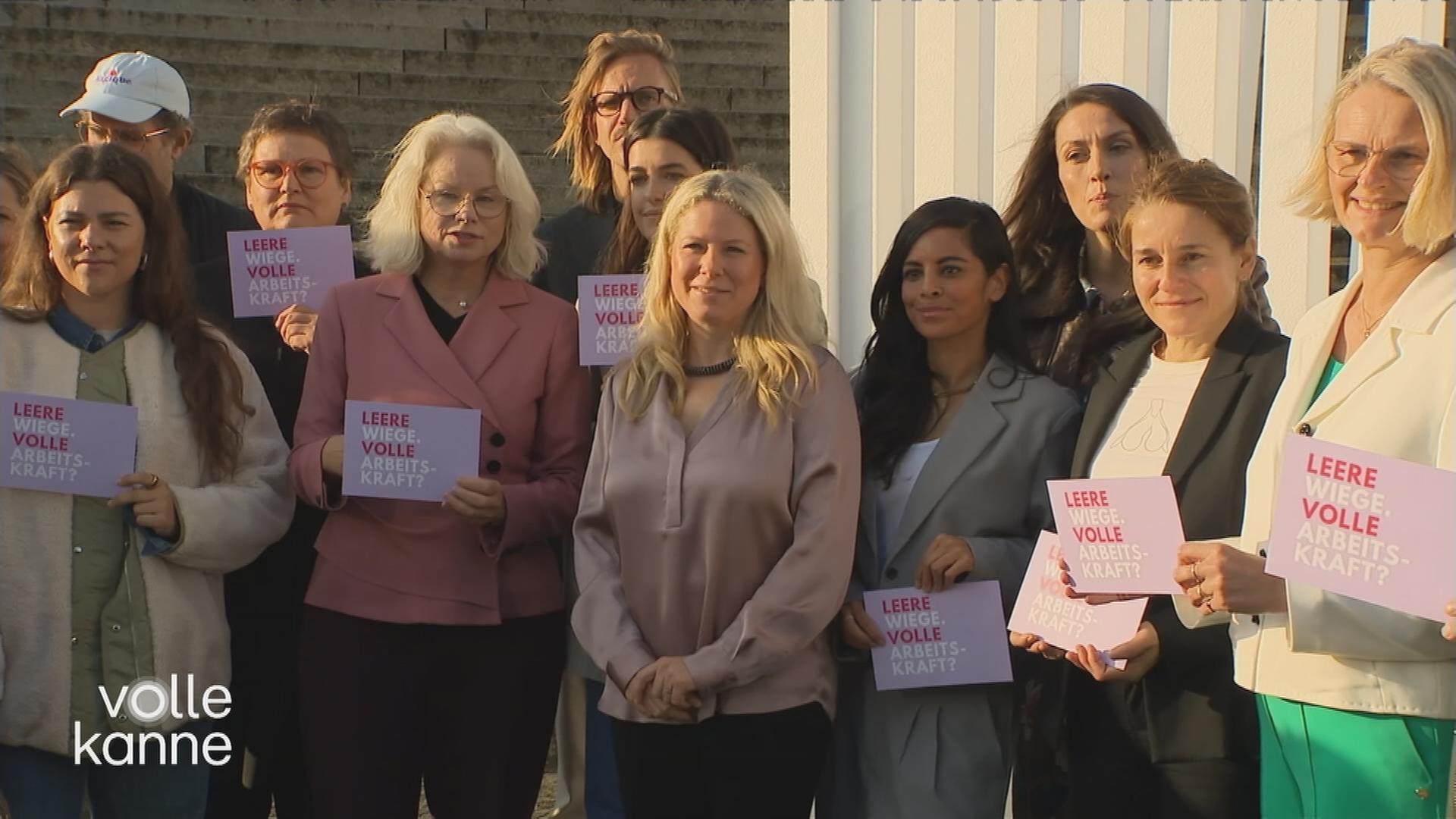 Frauen stehen in einer Reihe und halten Schilder hoch mit der Aufschrift "Leere Wiege, volle Arbeitskraft?"