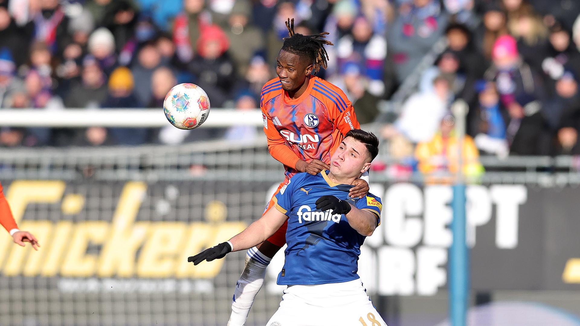 Schalkes linker Verteidiger Moussa Ndiaye springt im Zweikampf mit Kiels Stürmer auf dessen Schulter