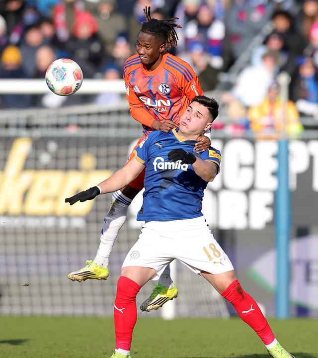 Schalkes linker Verteidiger Moussa Ndiaye springt im Zweikampf mit Kiels Stürmer auf dessen Schulter