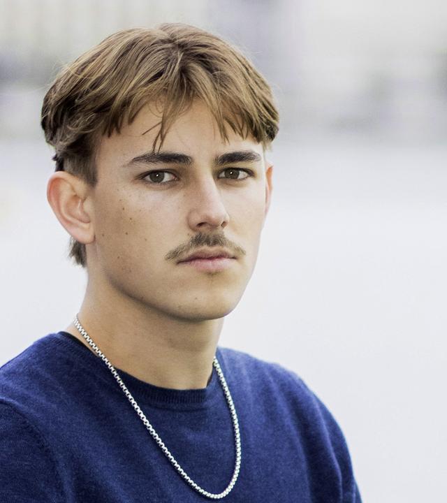 Porträtfoto eines jungen Mannes mit Oberlippenbart.