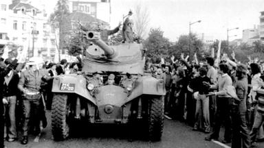 Eine schwarz-weiß Aufnahme von der Nelkenrevolution in Lissabon, Portugal. Ein Panzer ist umringt von begeisterten Menschen.