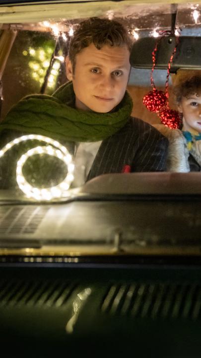 "Nelly und das Weihnachtswunder": Sonny (Rafael Gareisen), Nick (Joah Lion Goetze) und Nelly (Anna Schudt) sitzen in einem Auto, das mit Lichtergirlanden im Inneren geschmückt ist. Nelly sitzt am Steuer, Sonny sitzt neben ihr, Nick sitzt hinter den beiden und hat einen Arm auf Nellys Rückenlehne gelegt. Alle schauen interessiert nach vorne.