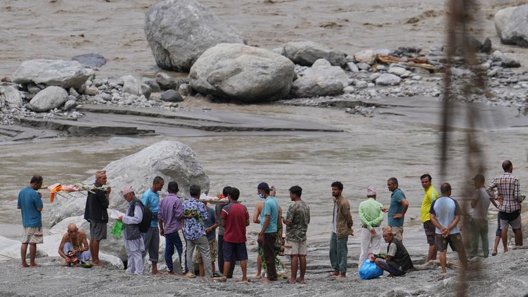  Menschen, deren Angehörige nach Sturzfluten weiterhin vermisst werden und als tot gelten, vollziehen am Ufer des angeschwollenen Trishuli-Flusses im nepalesischen Distrikt Nuwakot symbolische Bestattungsriten.
