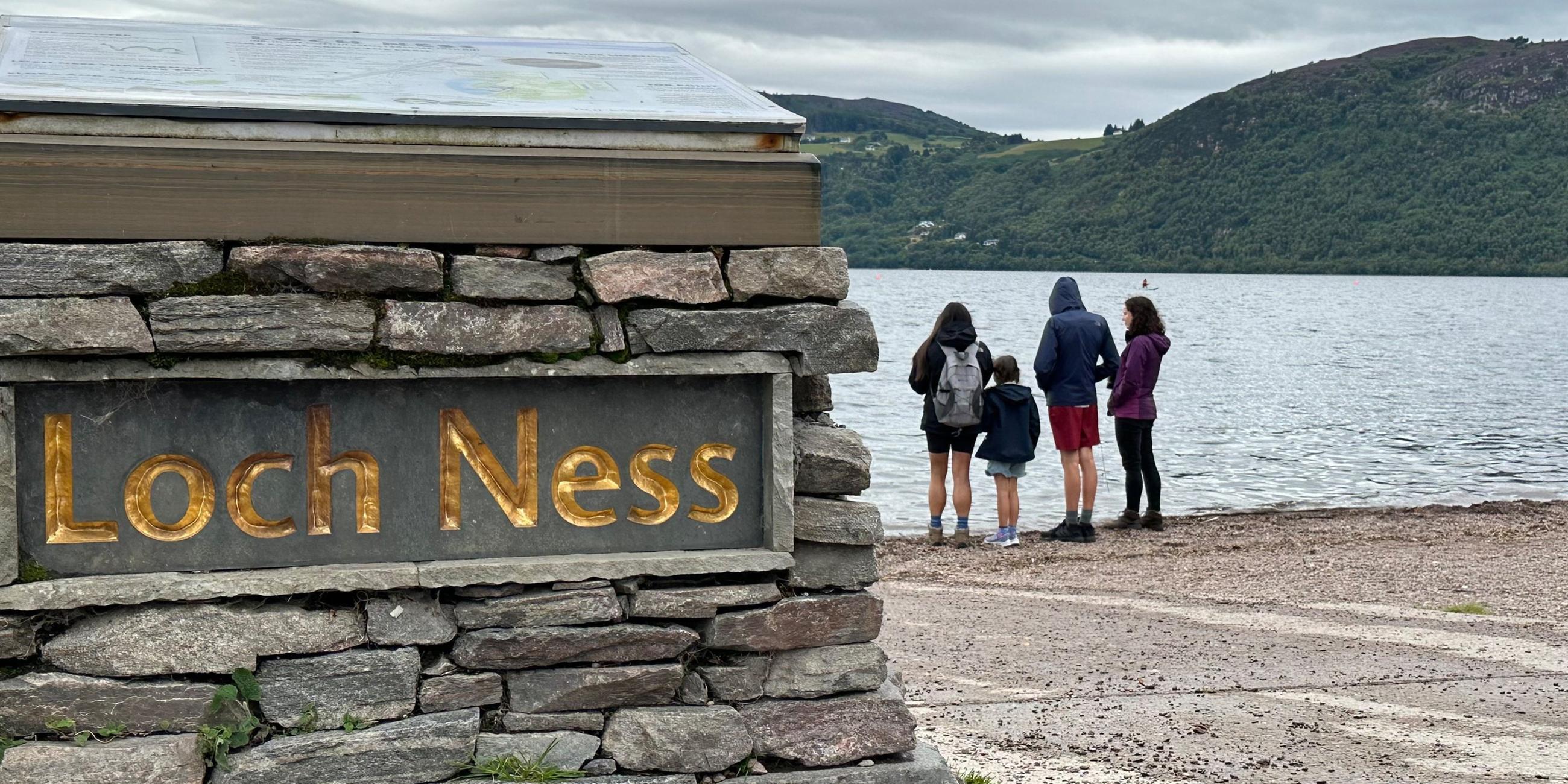 Großbritannien, Dores: Menschen stehen am Ufer des Loch Ness.