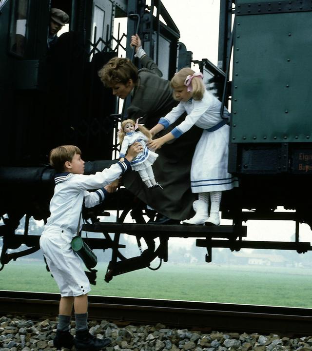 "Nesthäkchen - Teil 2": Klaus (Florian Baier) steht auf den Gleisen und reicht Annemarie (Kathrin Toboll) und Kindermädchen Lena (Susanne Uhlen) Annemaries Puppe.