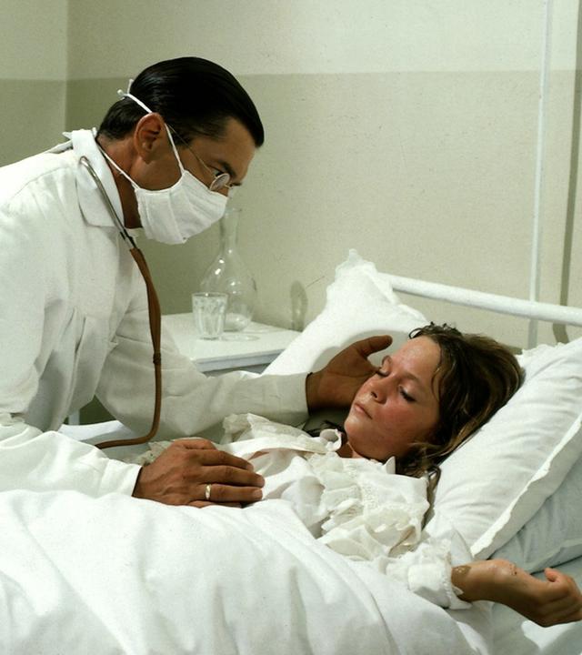 "Nesthäkchen - Teil 5": Annemarie (Anja Bayer) liegt krank im Bett. Ihr Vater (Christian Wolff) hört sie ab.