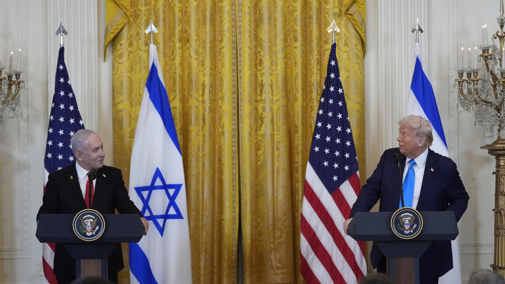 Trump und Netanjahu, schauen sich an, beide an Rednerpulten stehend.