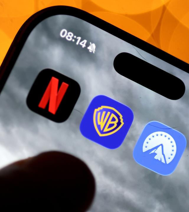 Auf einem Handy sind die Apps von Netflix, Paramount und Warner Bros. nebeneinander zu sehen.