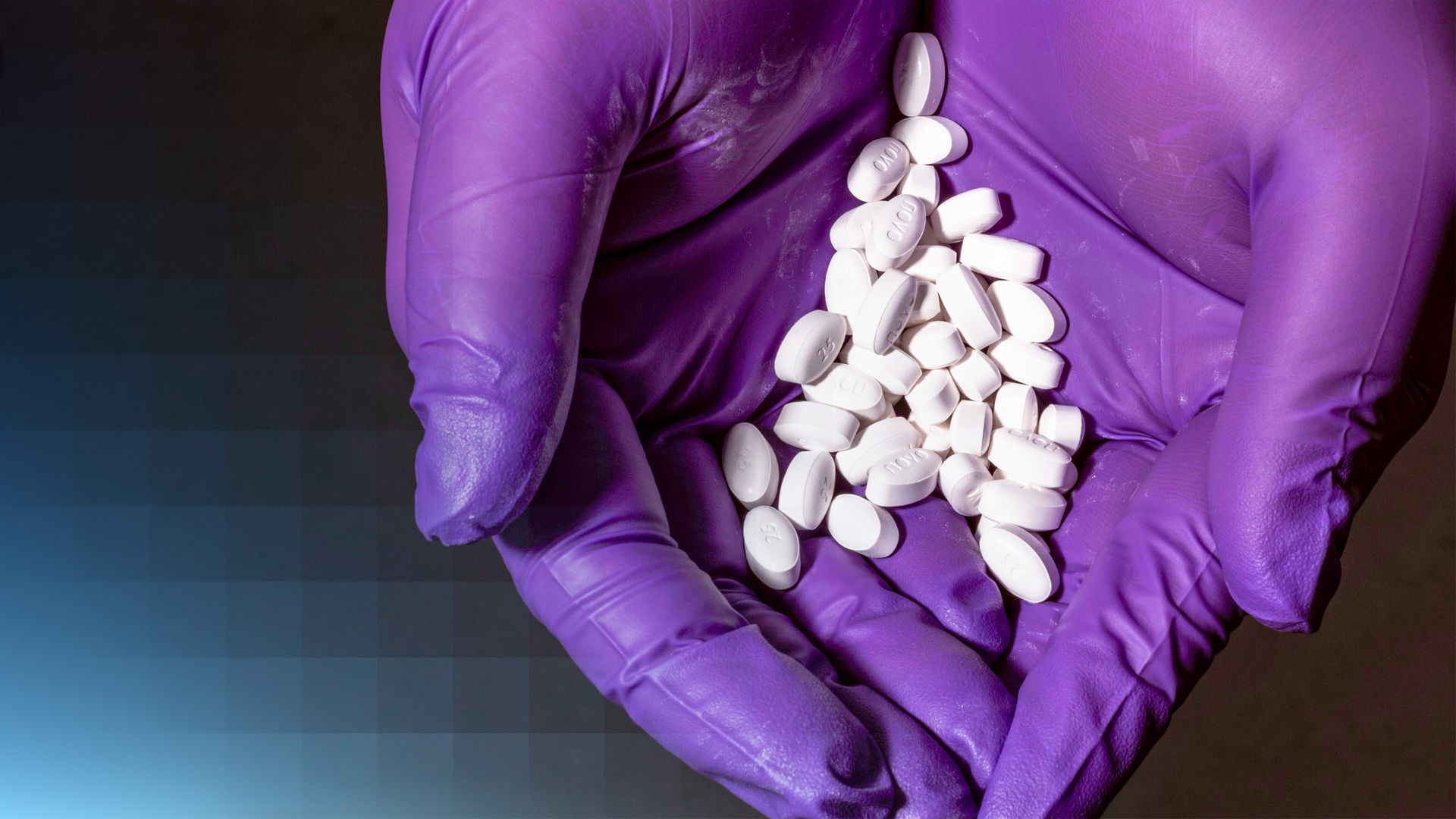 In einer mit Handschuhen bedeckten Hand liegen zahlreiche Tabletten