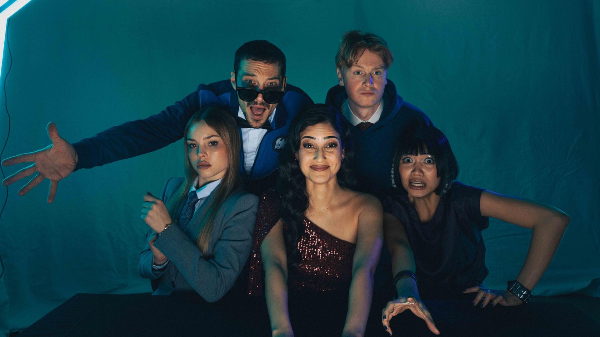 Zwei Darsteller und drei Darstellerinnen der neuen Coedy-Serie "SpyOn" mit unterschiedlicher Gestik und Mimik schauen in die Kamera