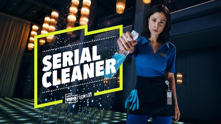 Titelbild der Serie „Serial Cleaner“: Eine Reinigungskraft hält eine Sprühflasche mit blauer Flüssigkeit und reinigt eine Scheibe. Neben ihr ist der Serientitel prominent eingeblendet, dahinter ein stilvoll beleuchteter Raum.