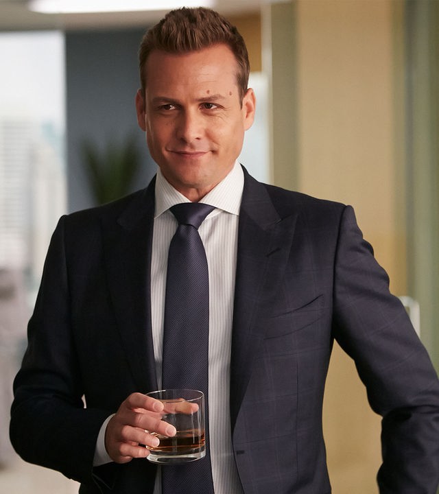 "Suits - Neue Ufer": Harvey (Gabriel Macht) steht in seinem Büro und hält elegant gekleidet mit einem siegesgewissen Gesichtsausdruck ein Whiskeyglas in der Hand.