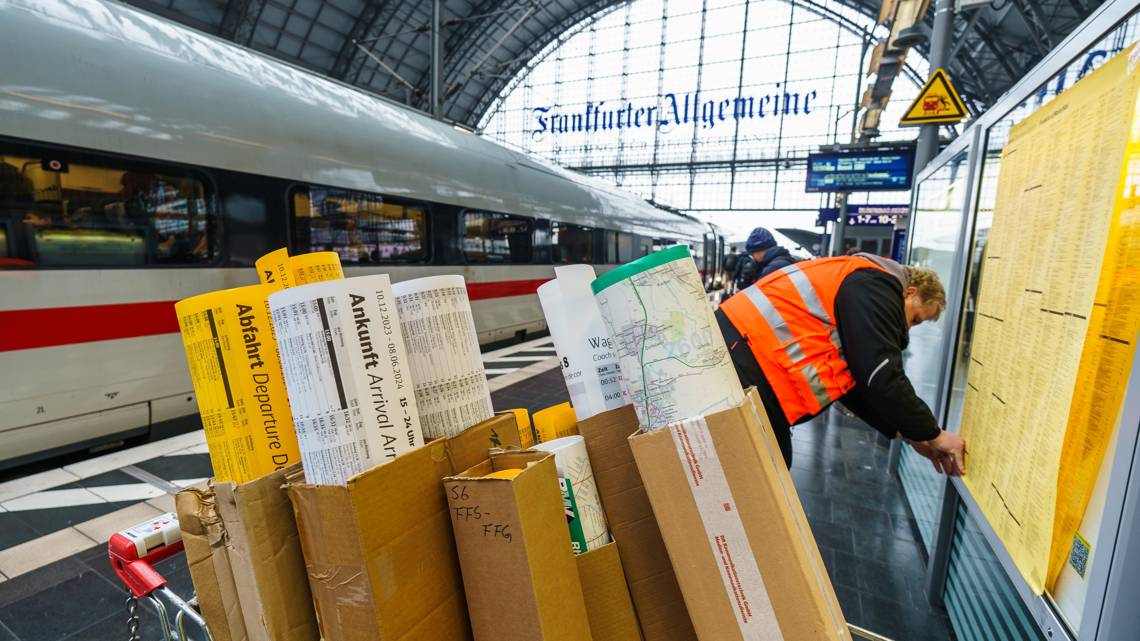Ein Mitarbeiter vom Bahnhofsmanagement hängt die neuen Fahrpläne in die Infokästen am Hauptbahnhof. 