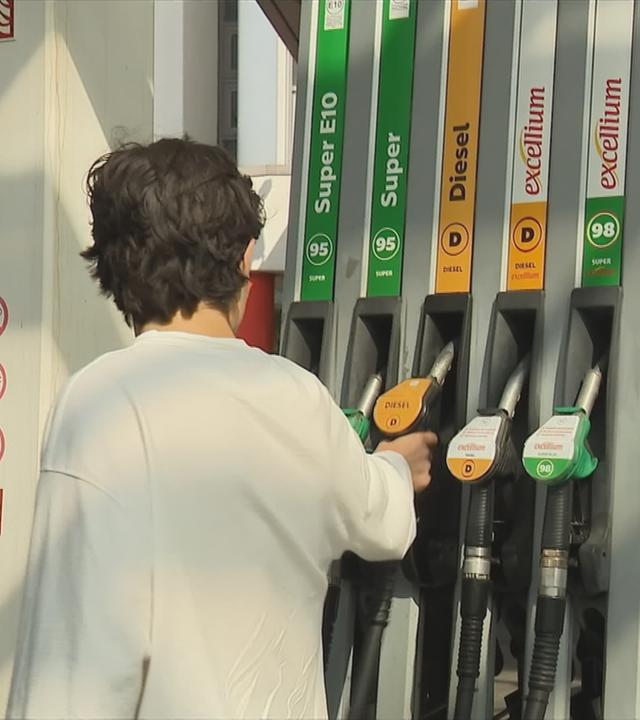 Ein junger Mann steht an der Zapfsäule einer Tankstelle