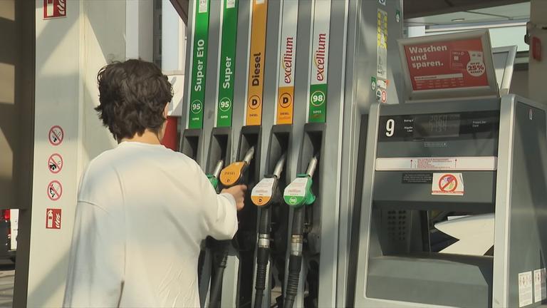 Ein junger Mann steht an der Zapfsäule einer Tankstelle