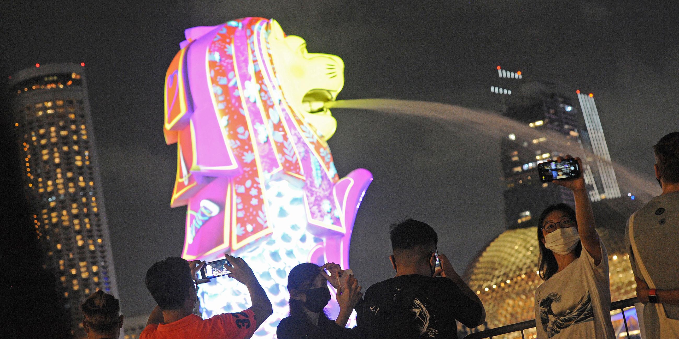 In Singapur filmen Zuschauer eine Lichtprojektion, die in der Stadt erleuchten.