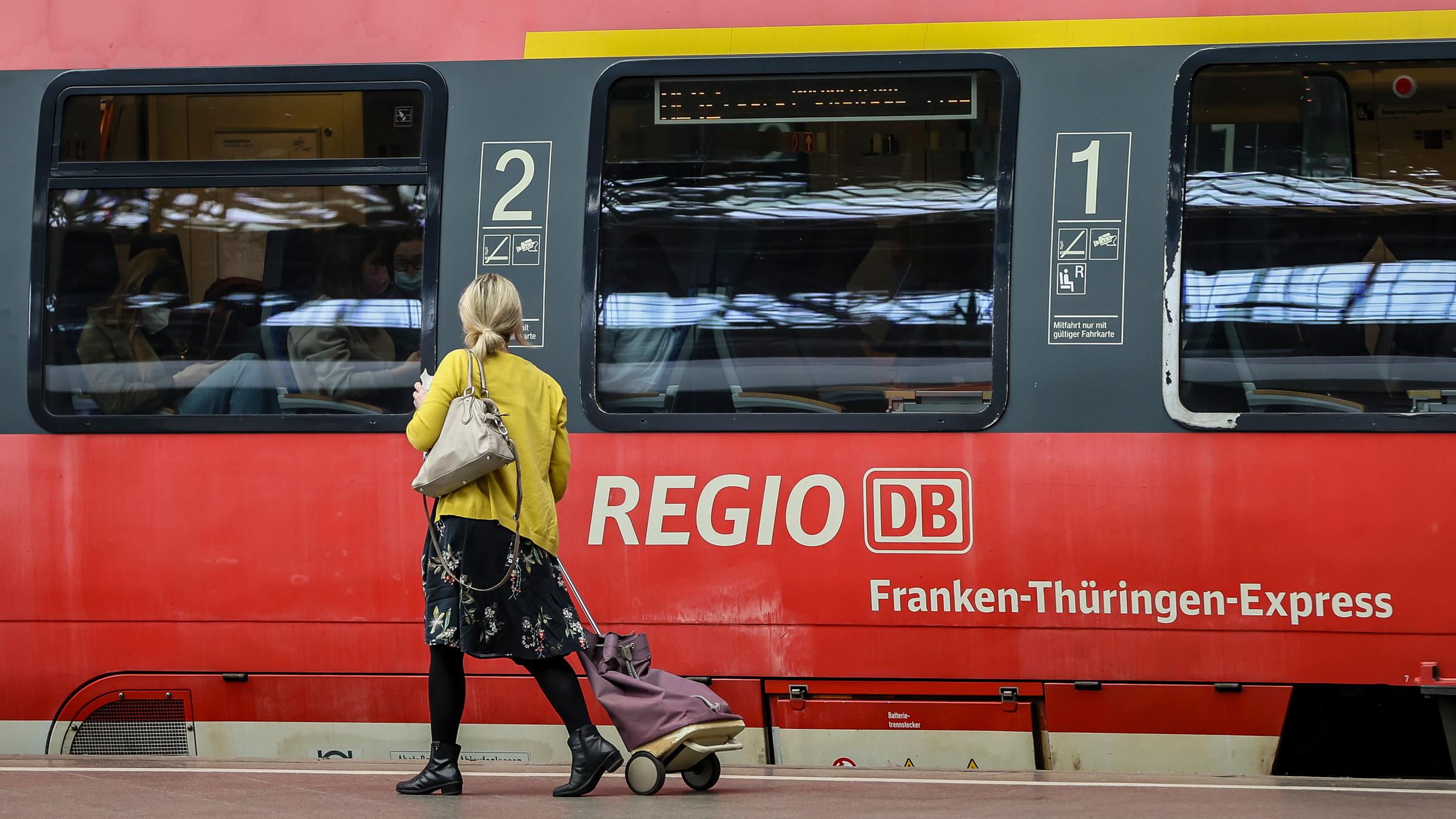 Eine Frau geht an einem Regionalexpress auf dem Hauptbahnhof Leipzig entlang