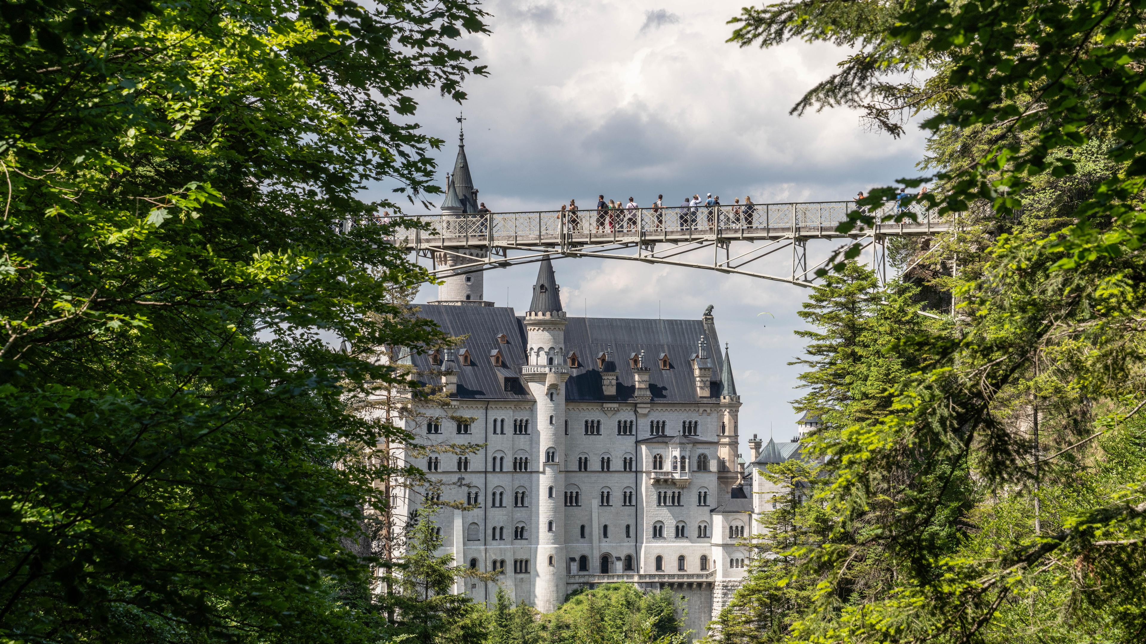 Zu sehen ist die Marienbrücke mit Menschen; im Hintergrund Schloss Neuschwanstein.