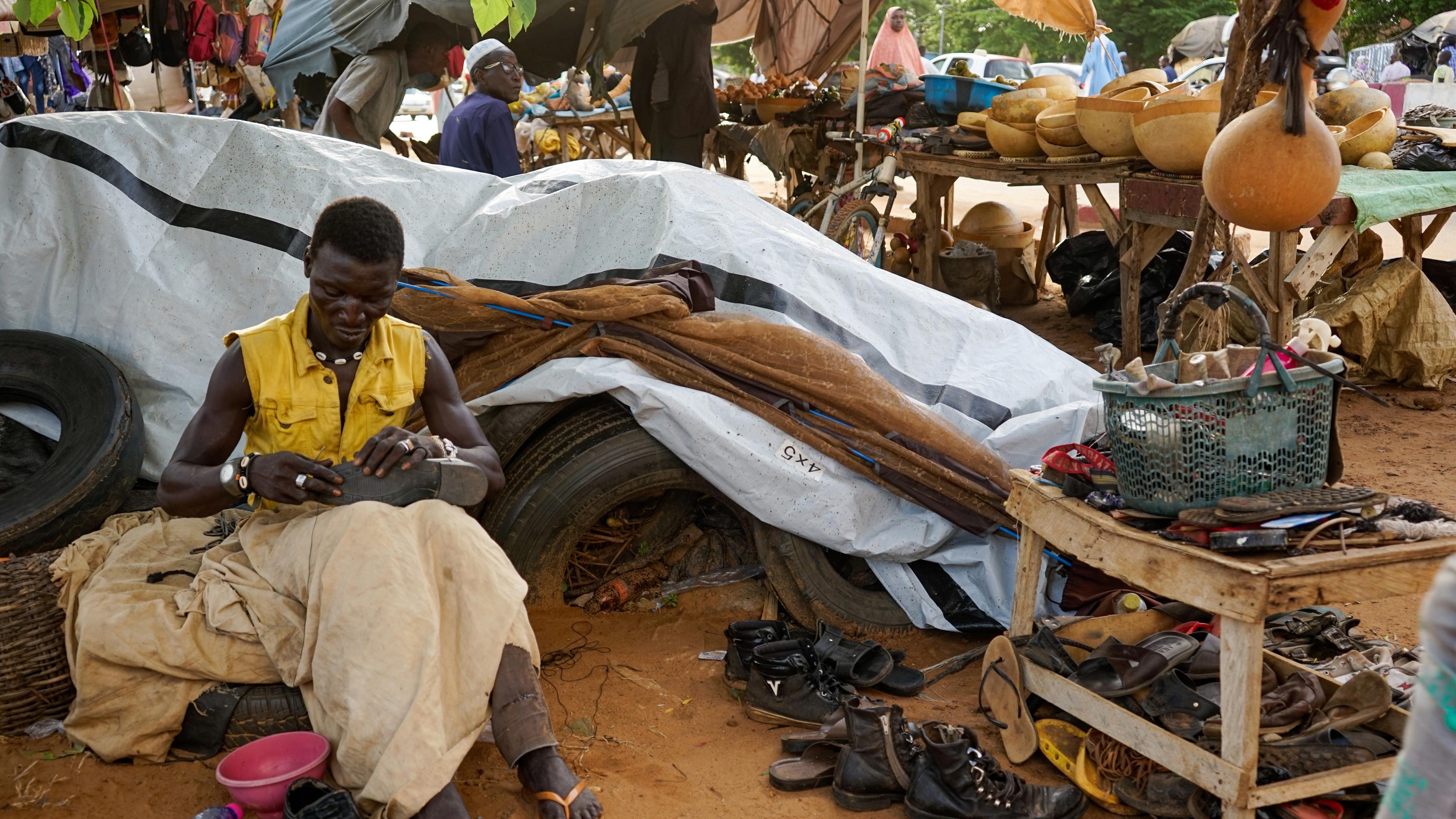 Ein Schuhmacher repariert Schuhe auf einem Markt in Niamey, Niger.