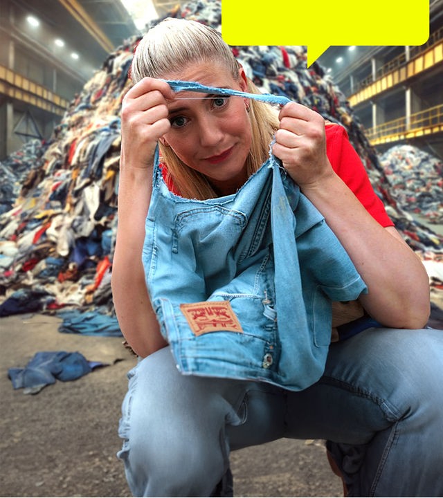 Pia Osterhaus sitzt vor einem Haufen alter Jeans und schaut durch das Loch einer kaputten Jeans.