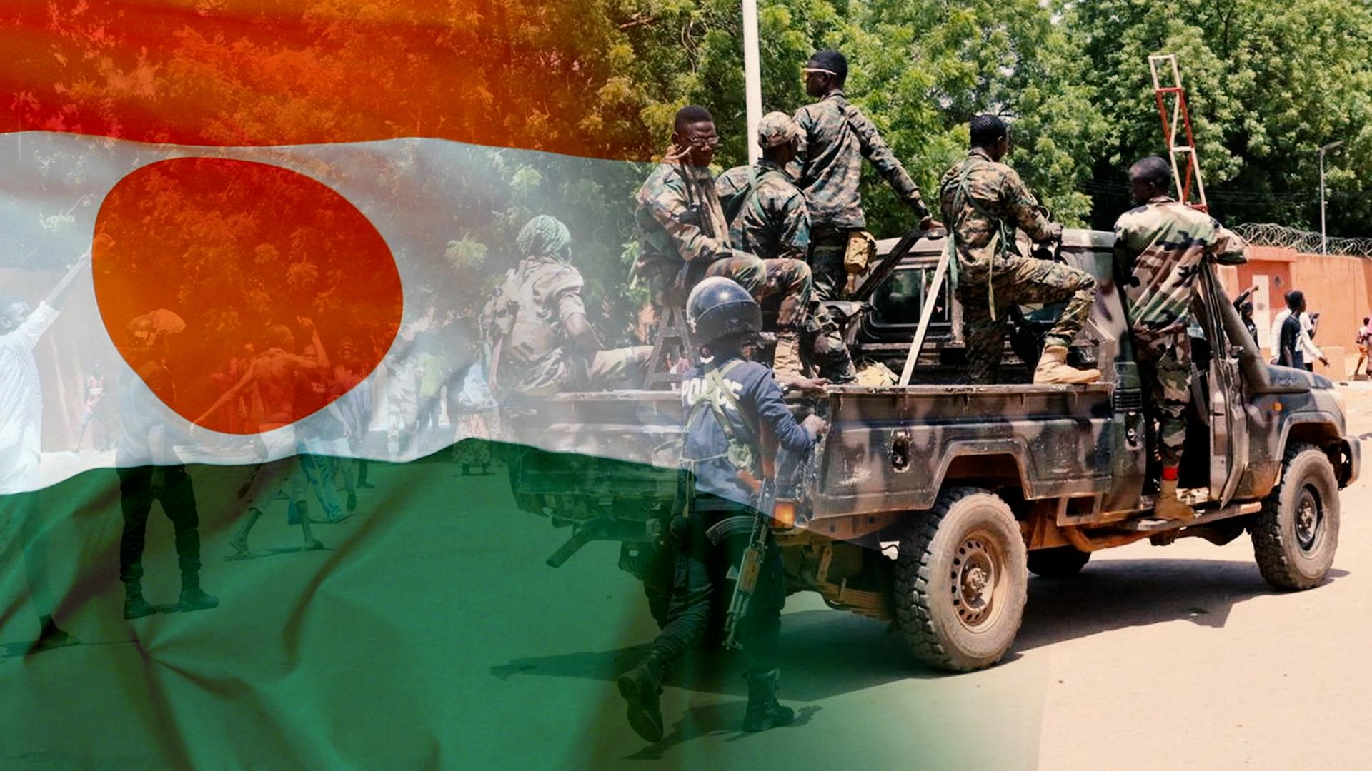 Soldaten auf einem Militärfahrzeug in Niger. Darüber die Fahne Nigers. 