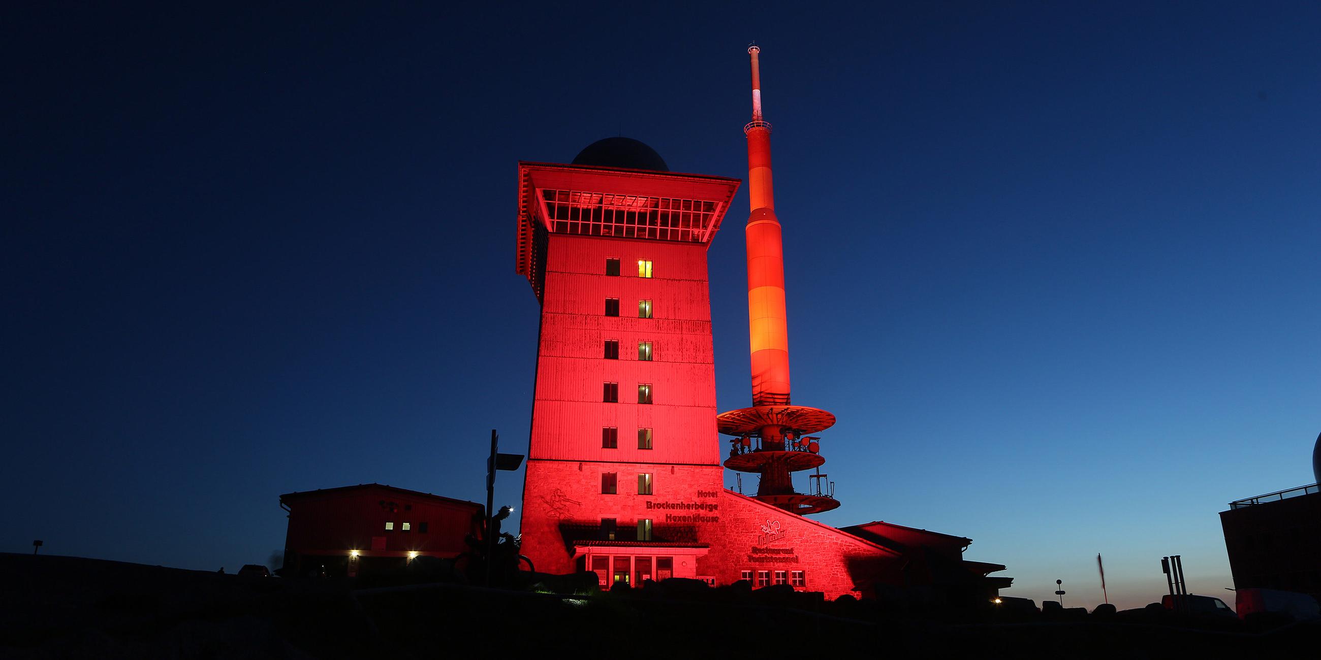Das Brockenhotel auf der höchsten Erhebung des Harz leuchtet in rotem Licht. 