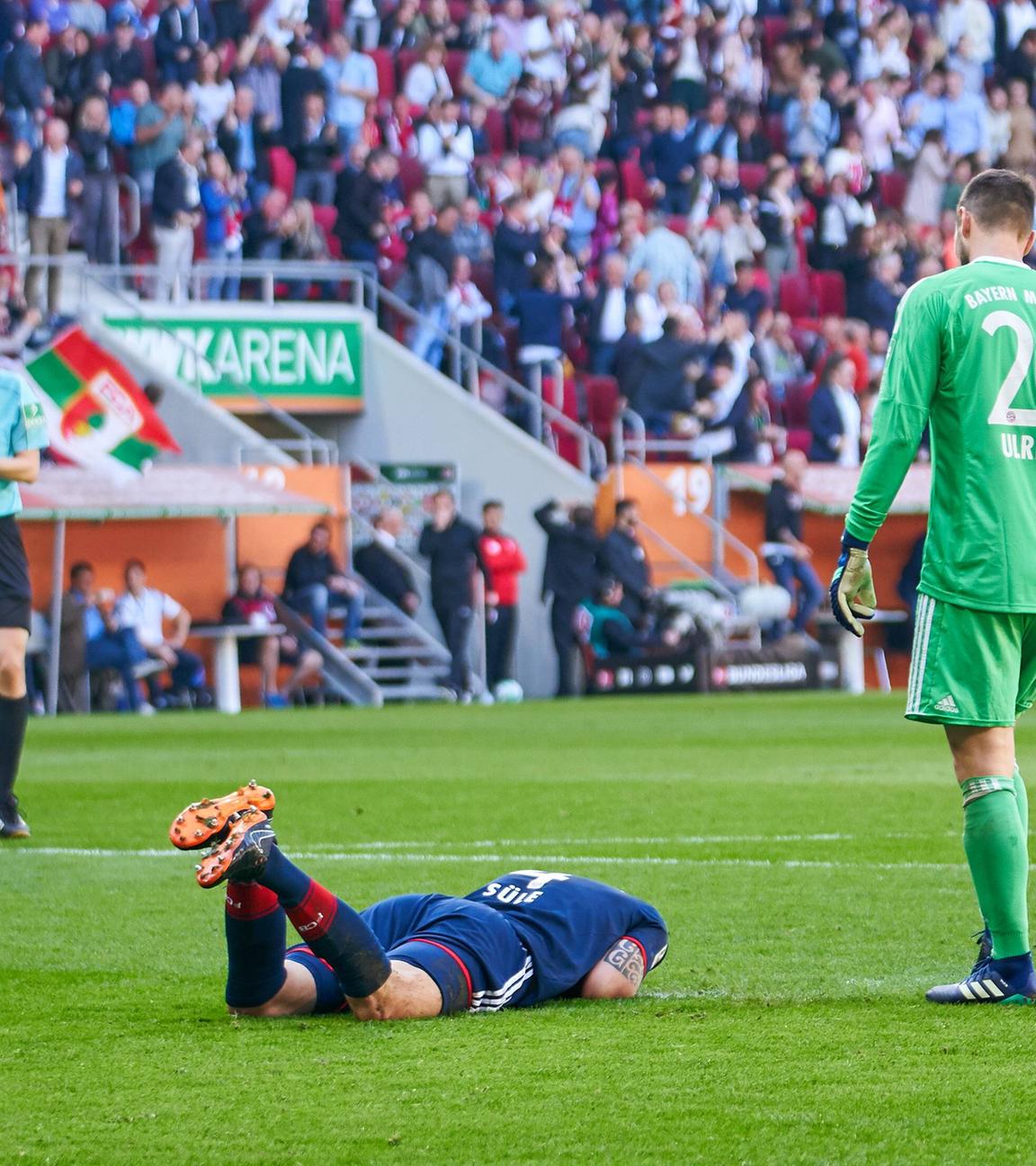 Niklas Süle liegt auf dem Boden nach einem Eigentor gegen Augsburg. Torhüter Manuel Neuer steht neben ihm.