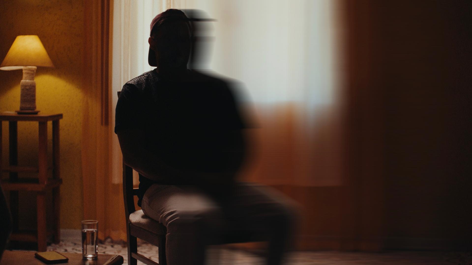 "Putins Krieger - Ein russischer Luftwaffen-Offizier packt aus": Ein Mann sitzt auf einen Stuhl Er ist nicht zu erkennen. Die hälte seiner Sihuette ist verschwommen.