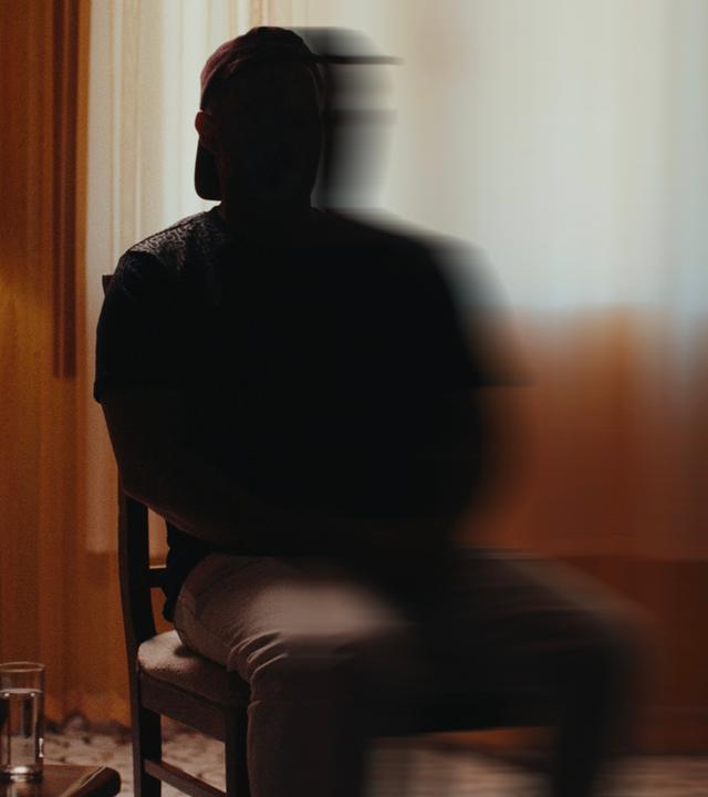 "Putins Krieger - Ein russischer Luftwaffen-Offizier packt aus": Ein Mann sitzt auf einen Stuhl Er ist nicht zu erkennen. Die hälte seiner Sihuette ist verschwommen.