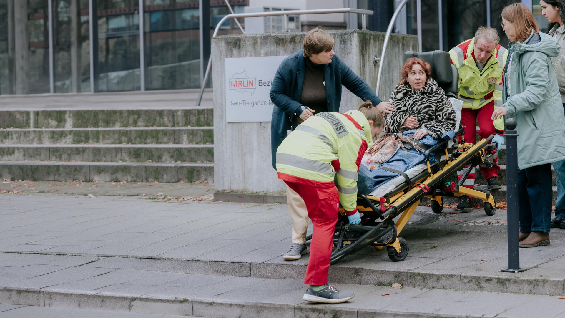 "Nine to Five - Das Amt - ABC Alarm": Doris (Kathrin Angerer) wird auf einer Trage von zwei Sanitätern (Komparsen) abtransportiert. Gisela (Petra Hartung), Conny (Lisa Hrdina), Dilara (Roxana Samadi) und Melissa (Anna Herrmann) haben sich um Doris versammelt.