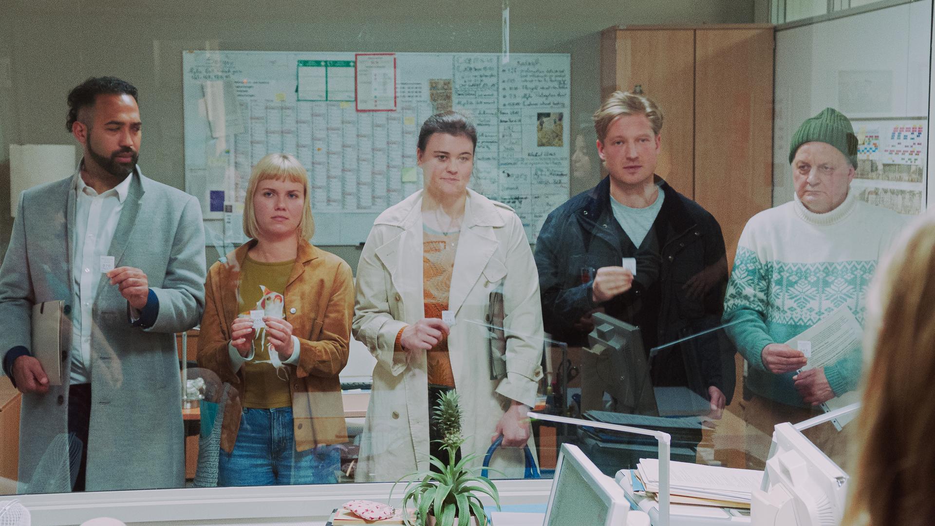 "Nine to Five - Das Amt - Vierte Etage": Die Kollegen (Rami El-Sheich Heussein, Sonja Gerter, Annemarie Franke, Anton Rubtsov, Stefan MÃ¼ser) stehen nebeneinander vor einer Glasscheibe im BÃ¼ro und blicken nach vorne.