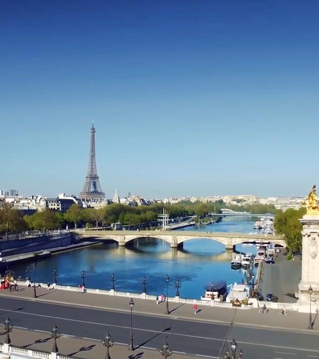 Paris mit Brücken über die Seine und Eiffelturm im Hintergrund.