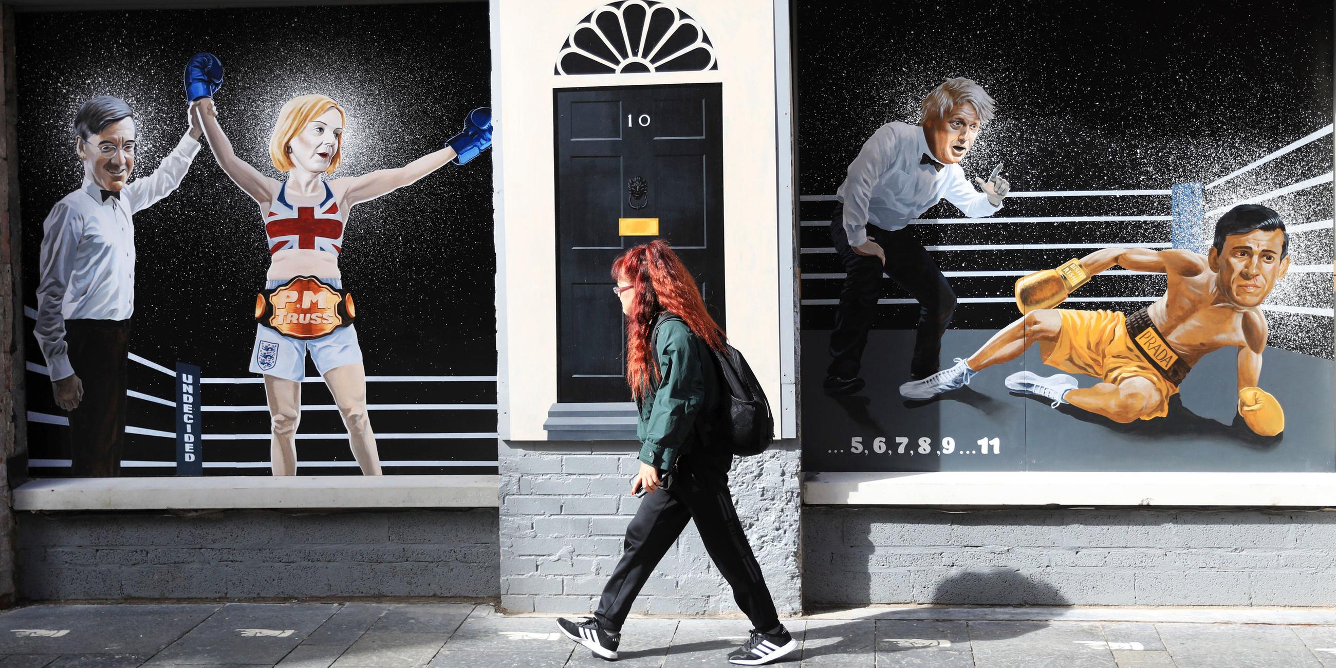 Eine Frau geht an einem politischen Wandgemälde des Künstlers Ciaran Gallagher in Belfast vorbei