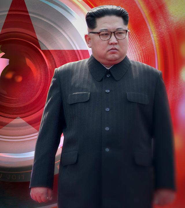 Kim Jong-un vor einer riesigen Kameralinse, dahinter angedeutet die Nordkoreanische Flagge.