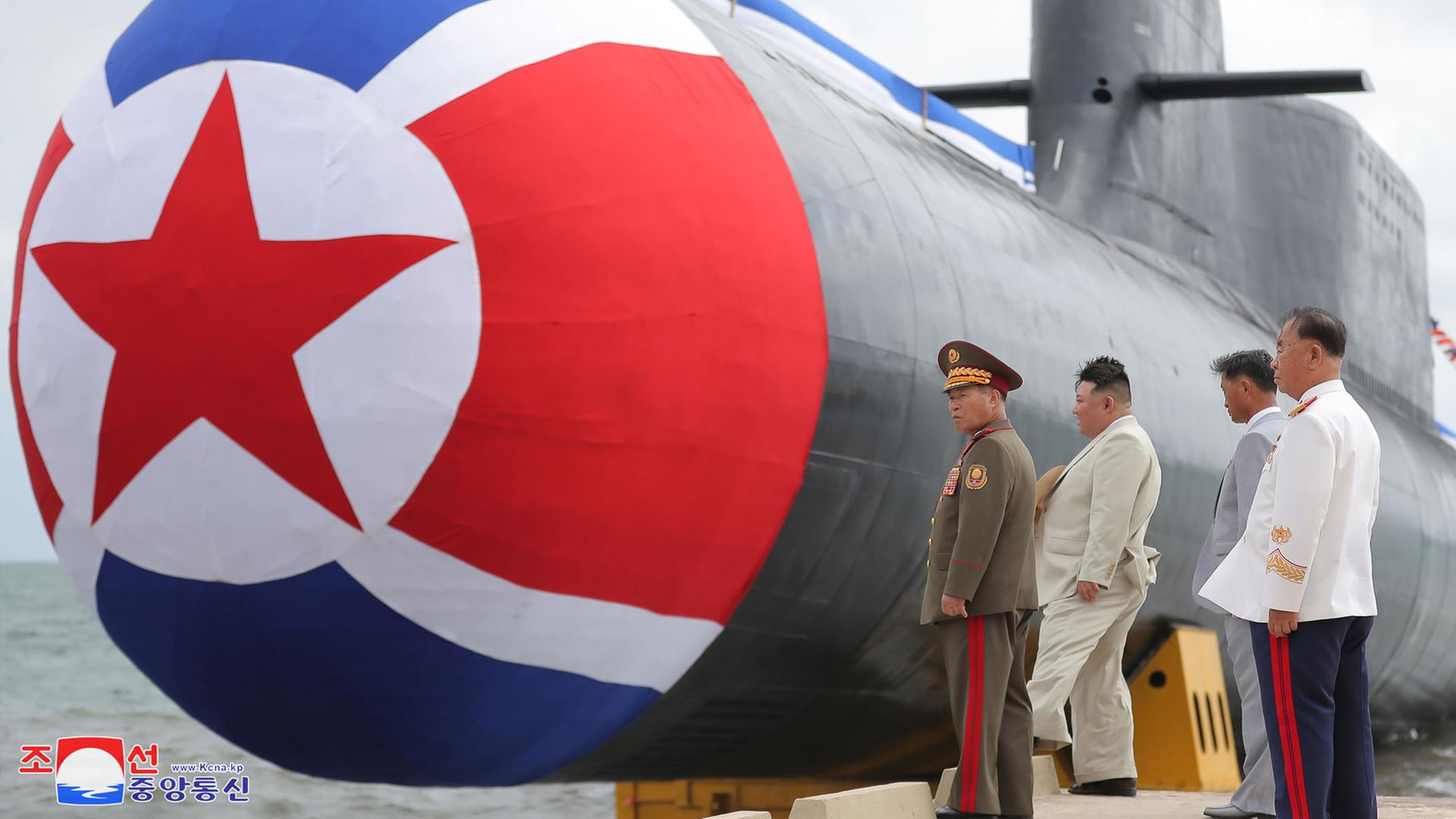 Zu sehen sind Nordkoreas Machthaber Kim mit Militär. Währenddessen wird ein nordkoreanisches U-Boot zu Wasser gelassen.