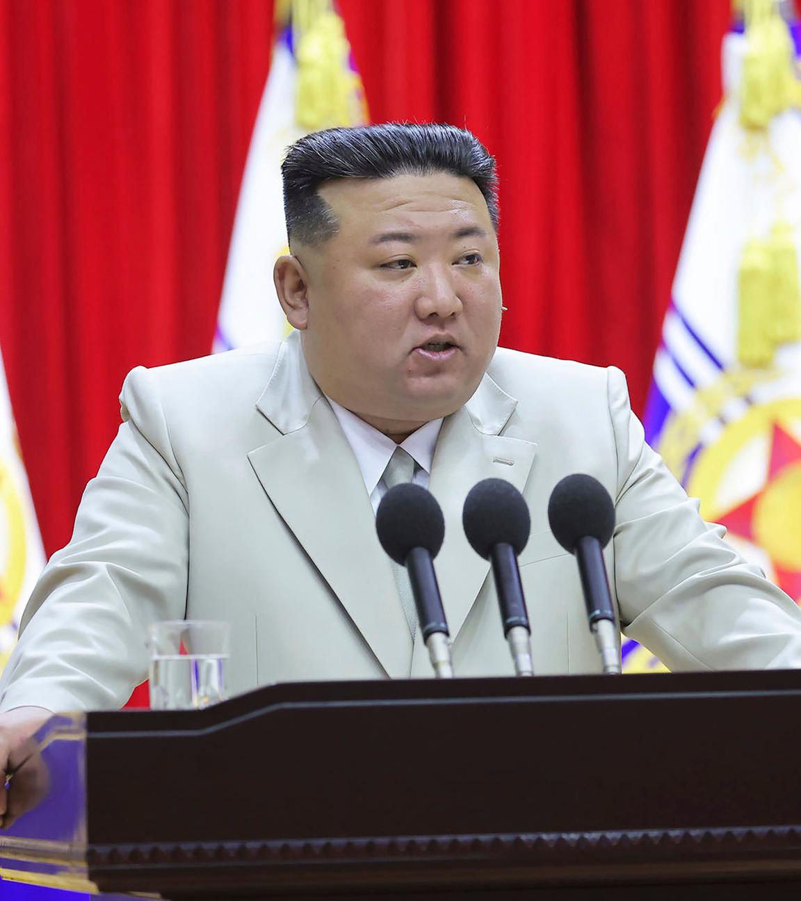 Kim Jong-un steht vor drei Mikrofonen im hellen Anzug.
