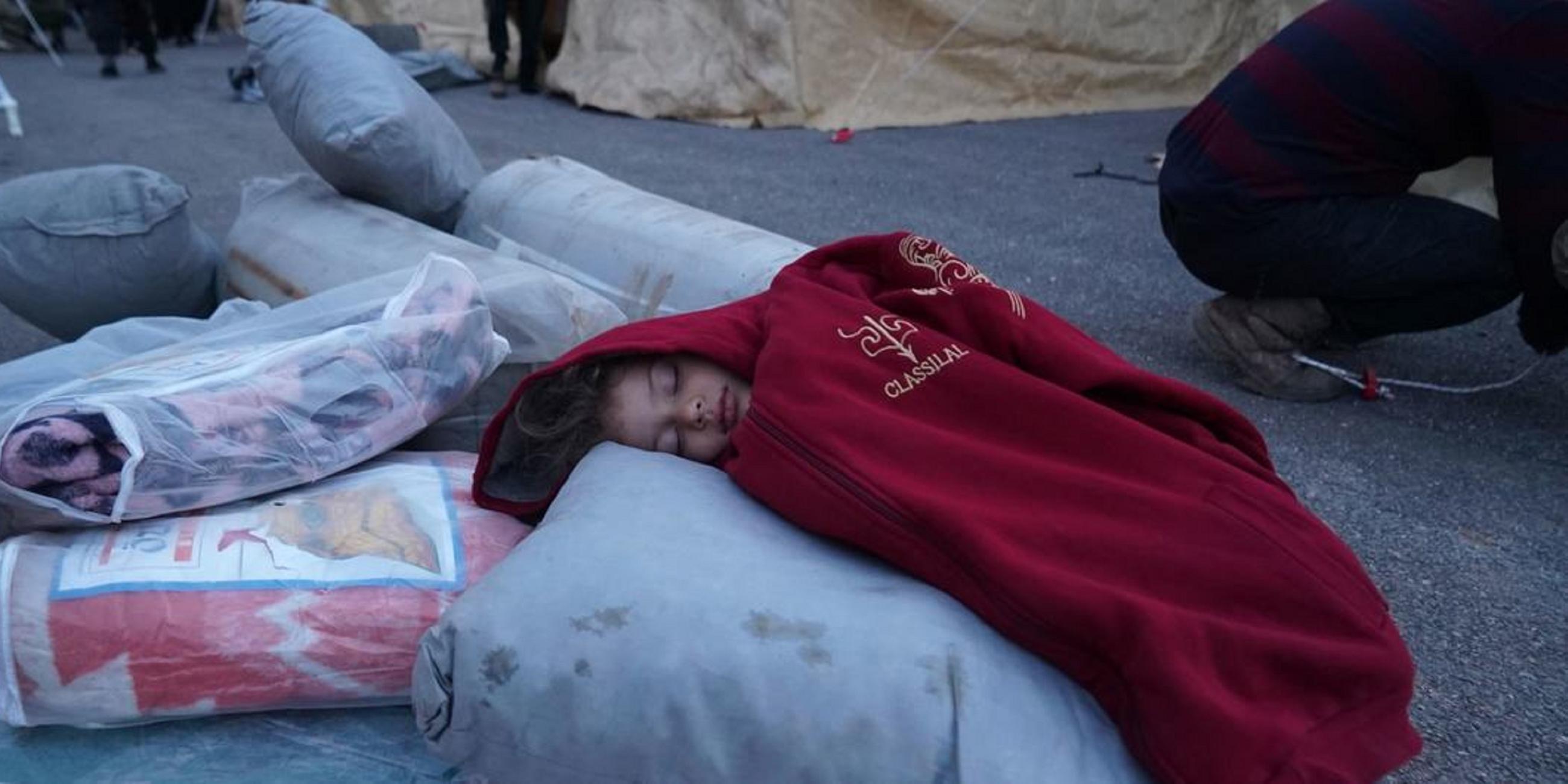 Ein Kind schläft auf Hilfsgütern in einem Aufnahmezentrum in der Stadt Jandairis in Nordsyrien.