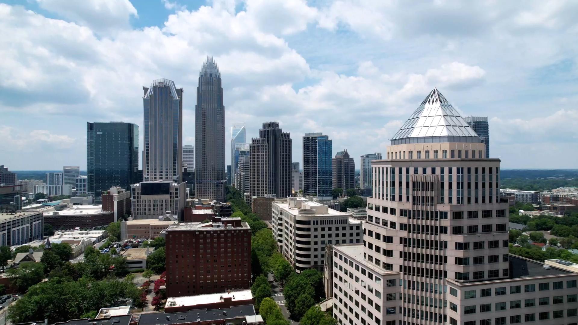 Skyline der Stadt Charlotte in North Carolina. Im Vordergrund steht ein Hochhaus mit einem markanten Spitzdach, im Hintergrund sind zahlreiche weitere Hochhäuser zu erkennen.