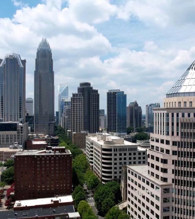 Skyline der Stadt Charlotte in North Carolina. Im Vordergrund steht ein Hochhaus mit einem markanten Spitzdach, im Hintergrund sind zahlreiche weitere Hochhäuser zu erkennen.