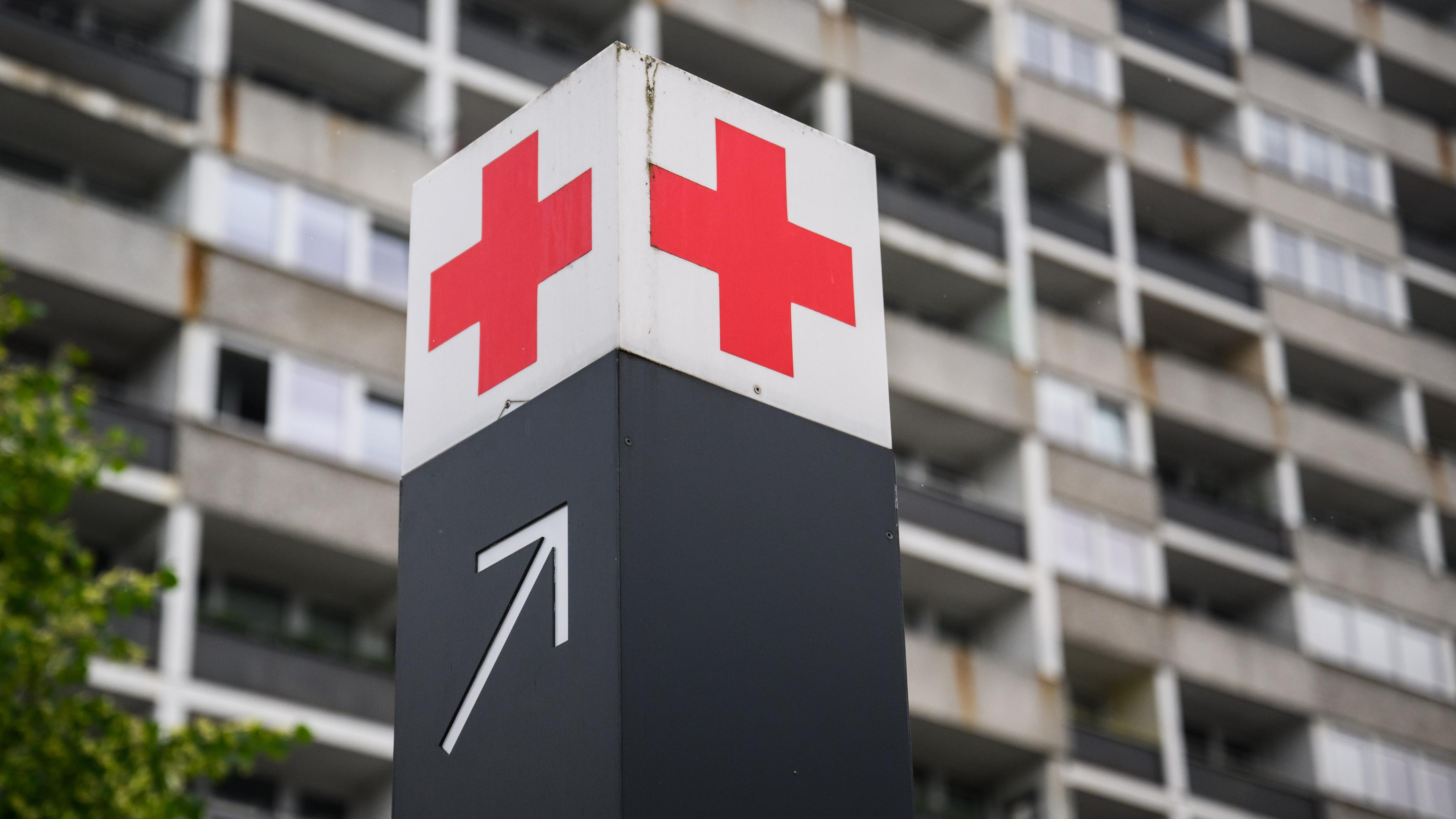 Ein Schild mit einem roten Kreuz weist den Weg zur Notaufnahme in einem Krankenhaus hin.