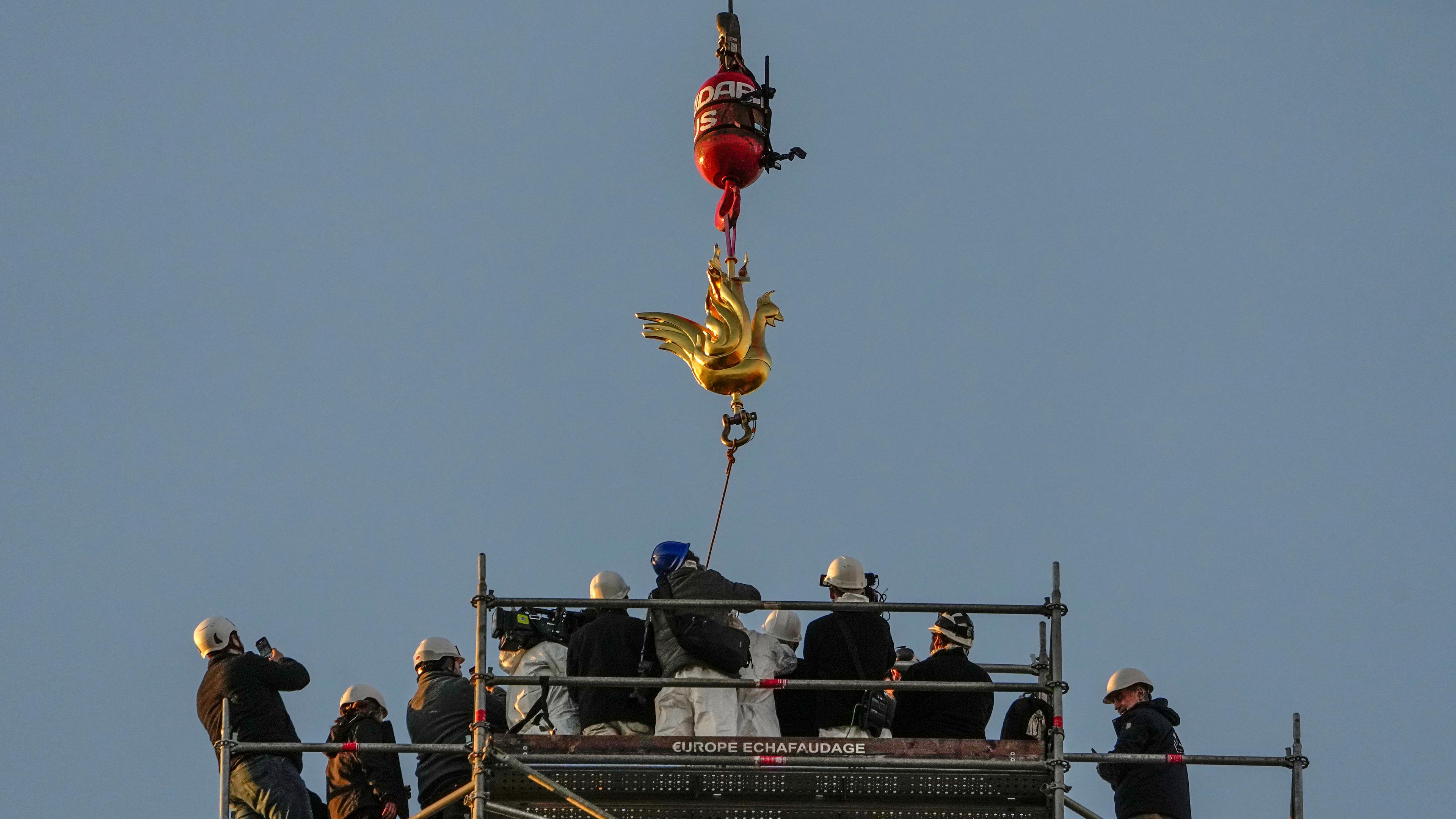 Der goldene Hahn wird mit einem Kran zurück auf die Spitze der Notre Dame gekurbelt.